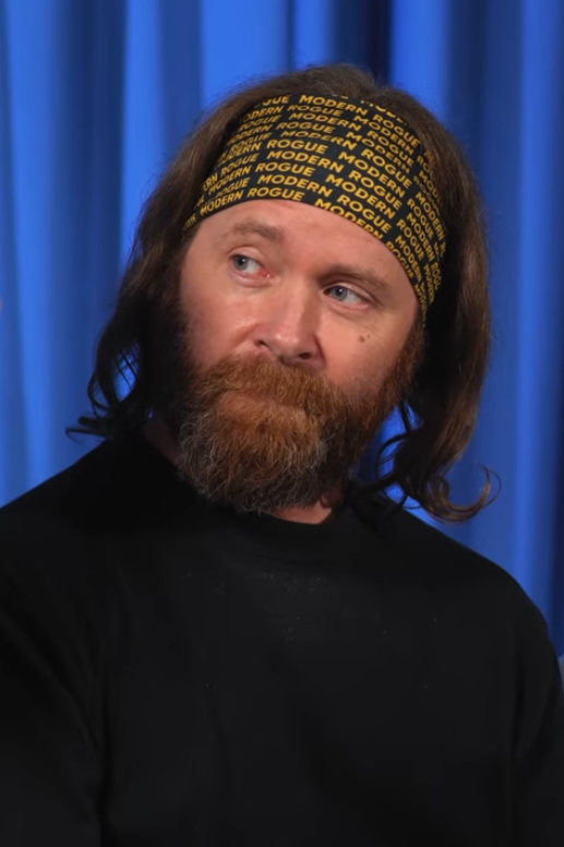 Man wearing headband and black shirt looks to his right