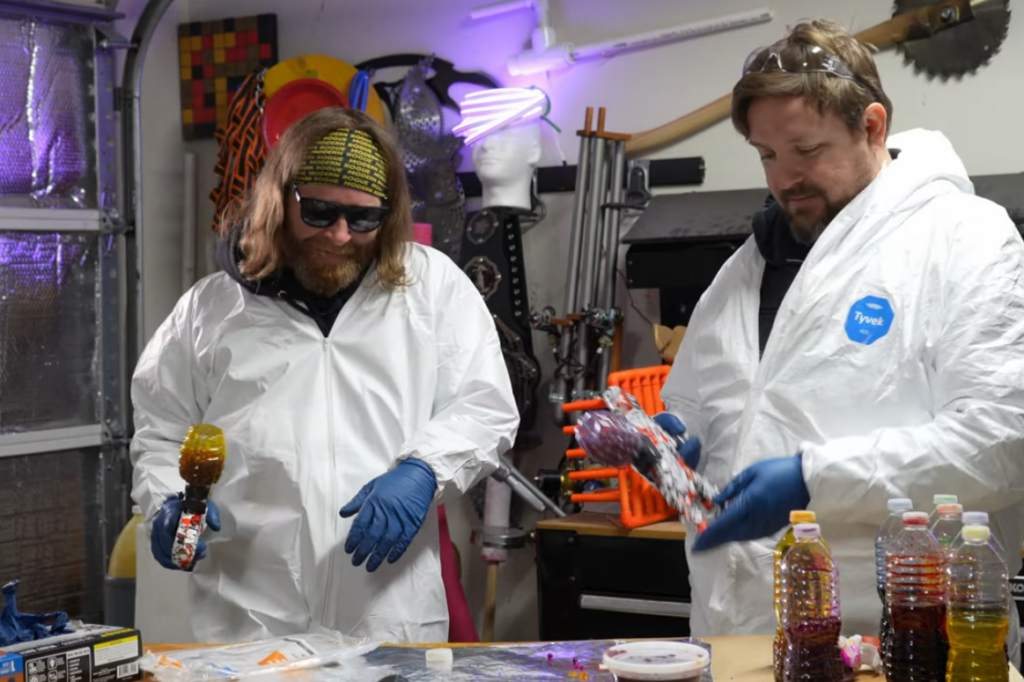 Two men wearing protective suits doing an odd garage experiment